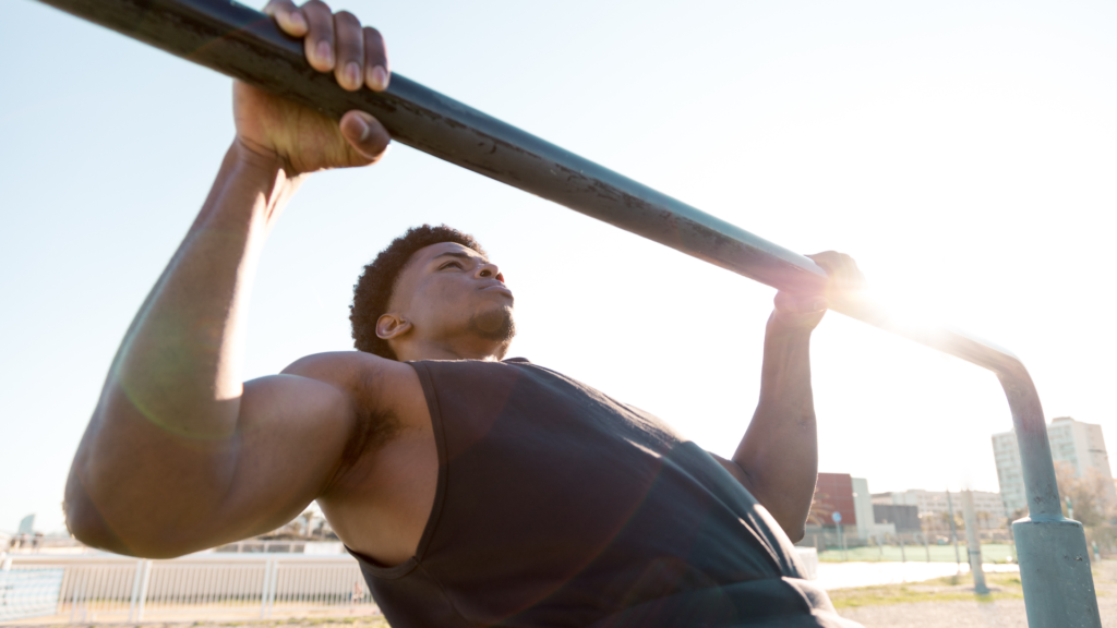Man performing a bodyweight row under the sun. This exercise is part of the beginner calisthenics workout plan.